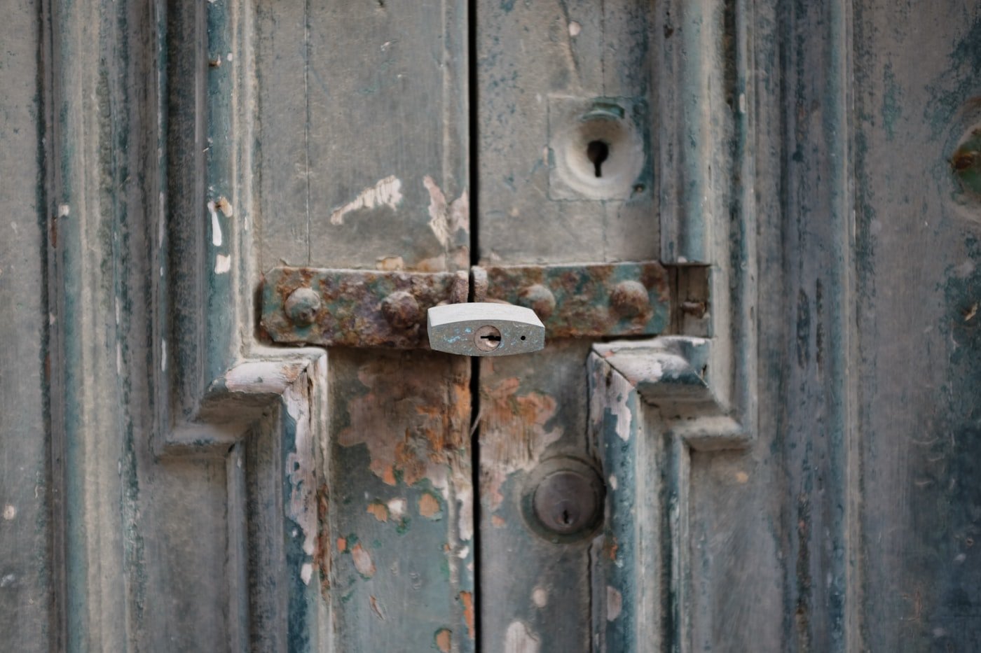 Padlock and rusted latch on a weathered timber door